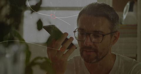 Man Speaking to Smartphone at Home Surrounded by Plants and Modern Decor