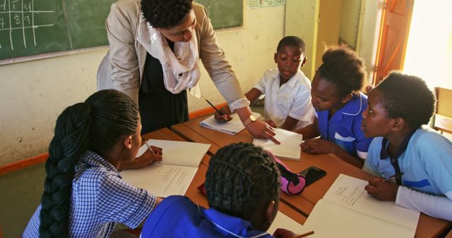 Teacher Guiding Students in Classroom Activity with Books and Notebooks - Download Free Stock Images Pikwizard.com