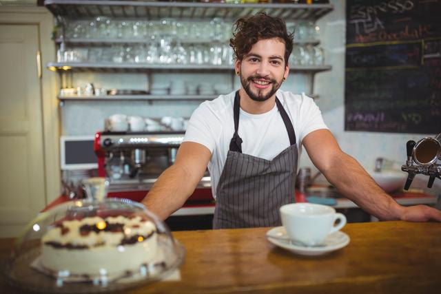 Portrait of smiling waiter standing at counter in cafÃ©