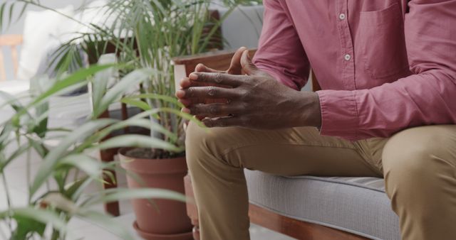 Close-Up of Pensive Man Sitting on Sofa with Green Plants Indoors - Download Free Stock Images Pikwizard.com