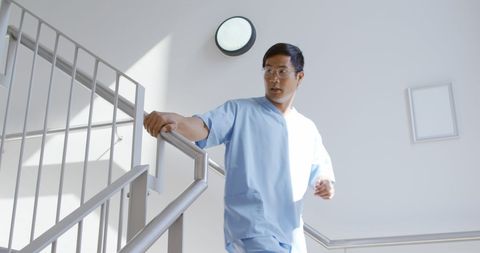 Asian Doctor Ascending Hospital Staircase with Purpose and Focus