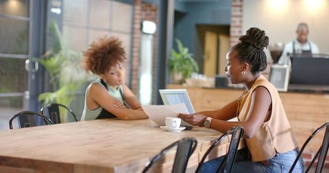 African american women meeting and reviewing documents at cafe coworking table