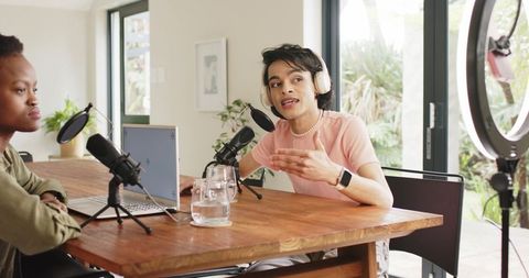 Diverse hosts recording conversational podcast at home studio with ring light and laptop