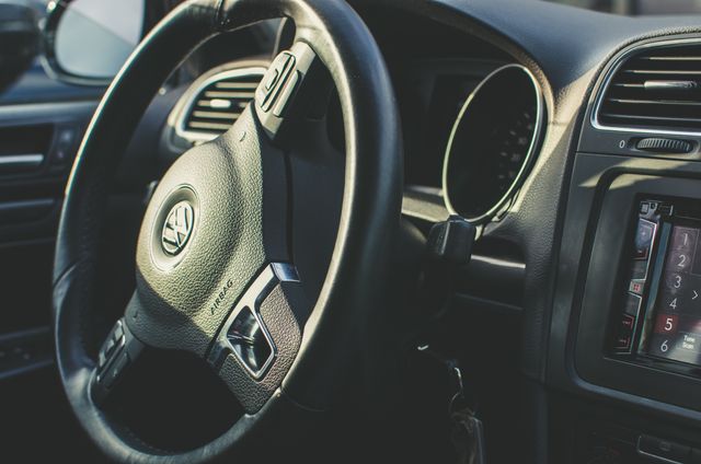 This image displays a close-up view of a modern car interior featuring a steering wheel and dashboard. This type of photo can be used for showcasing automotive technology, car detailing, luxury vehicle advertisements, driver training materials, or transportation-related publications.
