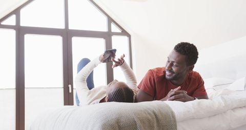 Couple Relaxing in Bedroom with Smartphone
