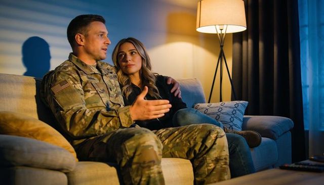 Us army soldier discussing reintegration with partner on couch in warm evening living room