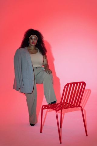 Mid 30s african american woman posing with draped blazer on red gradient backdrop