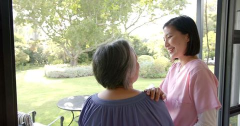 Caregiver Supporting Elderly Woman Outdoors in Garden Setting