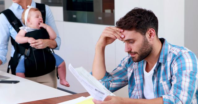 Stressed Father Managing Finances While Wife Cares for Crying Baby - Download Free Stock Images Pikwizard.com