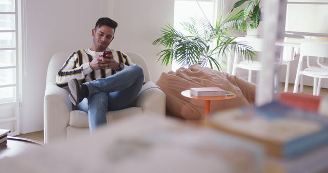 Young Man Relaxing on Chair Using Smartphone in Bright Modern Living Room - Download Free Stock Images Pikwizard.com
