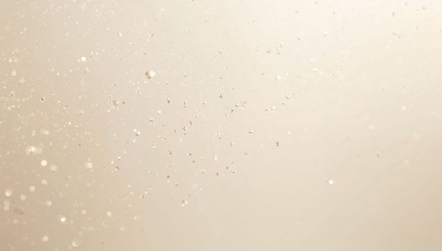 Soft beige bokeh with floating dust and water droplets, airy macro texture for background