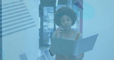 Multitasking professional holding file and talking on phone in office with data graphics