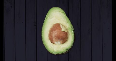 Fresh Avocado Halved on Dark Wooden Background
