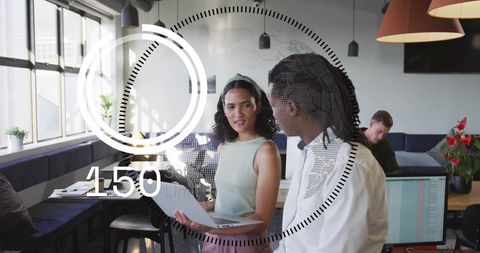 Young professionals discussing project in modern coworking space with laptop HUD overlay