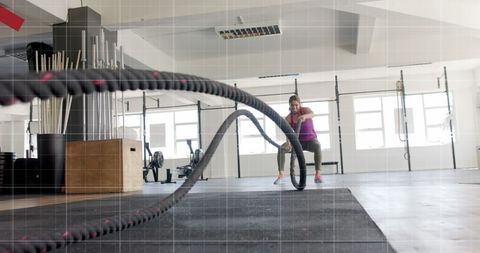 Caucasian woman engaging battle rope training in modern gym setting