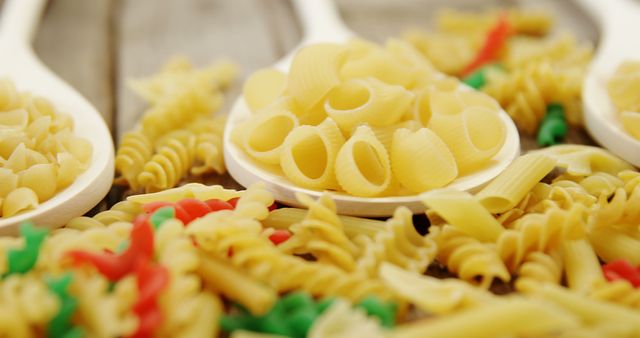 Assorted Uncooked Pasta on Wooden Spoons and Surface - Download Free Stock Images Pikwizard.com