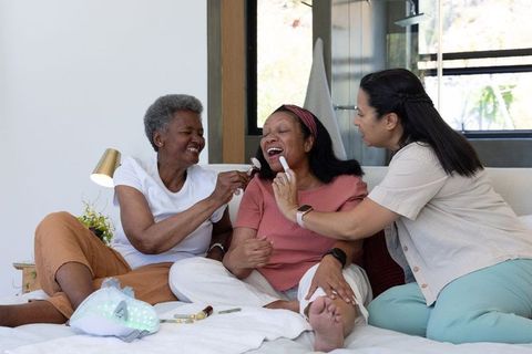 Multigenerational african american women laughing and applying makeup during home pampering