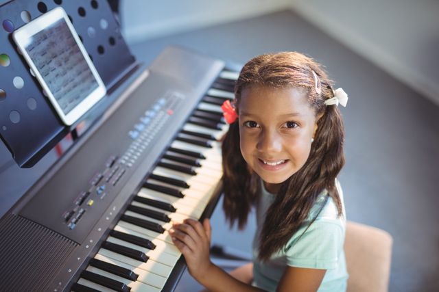 Young girl practicing piano in a school music class. Ideal for educational materials, music education promotions, school brochures, and articles on childhood learning and development.