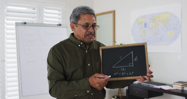 Biracial male teacher standing at a whiteboard giving an online lesson to camera. education at home in self isolation during quarantine lockdown.