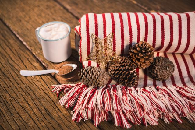 Rolled blanket with pine cone and coffee mug on wooden table