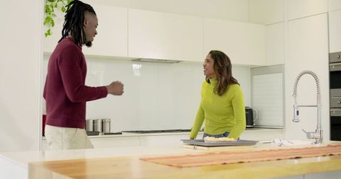 Multicultural couple baking pastries on bright modern kitchen island, joyful home cooking