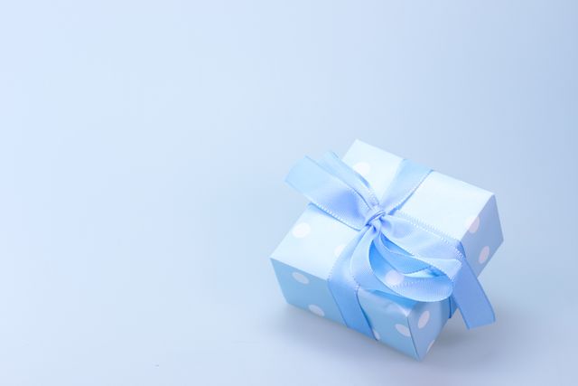 Beautifully wrapped blue gift with polka dot pattern and ribbon is perfectly suitable for any special occasion, celebrating birthdays, anniversaries, or festive holidays. Excellent choice for greeting cards, blog posts about gift-giving, and promotional materials for gift shops.