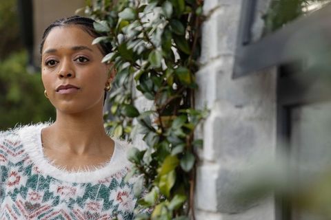 African american woman posing by vine-covered wall wearing fuzzy geometric sweater