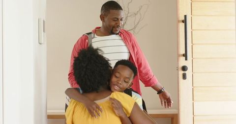 Heartfelt african american family hug at front door celebrating homecoming and warm welcome