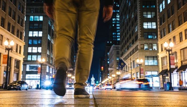 Walking through urban night street with motion blur light trails and city lights