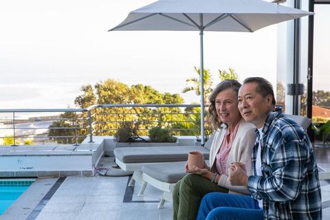 Relaxed Senior Couple Enjoying Coffee by Scenic Poolside