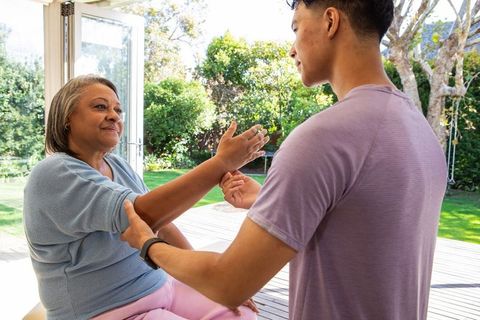Caring Young Man Assisting Elderly Woman in Outdoor Stretching Session