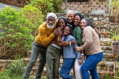 Multigenerational african american family hugging and smiling on stone garden steps