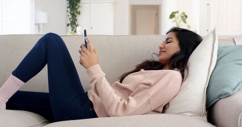 Woman Relaxing on Couch Using Smartphone in Modern Living Room