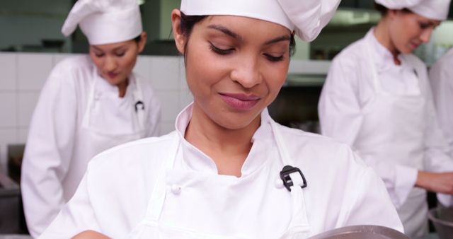 Female chefs in uniform engaged in food preparation in a professional kitchen setting. Perfect for illustrating culinary school advertisements, restaurant promotions, food magazines, and articles about professional cooking and gastronomy.