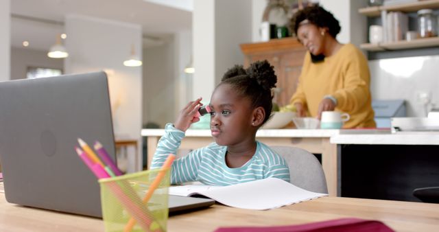 Little Girl Studying with Laptop While Mother Cooking in Background - Download Free Stock Images Pikwizard.com