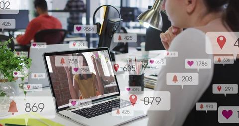 Woman Watching Video Call on Laptop in Open Office with Social Notifications Overlay