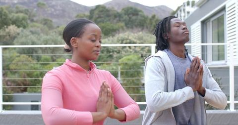 Couple Practicing Meditation on Sunlit Terrace with Mountain View for Wellness