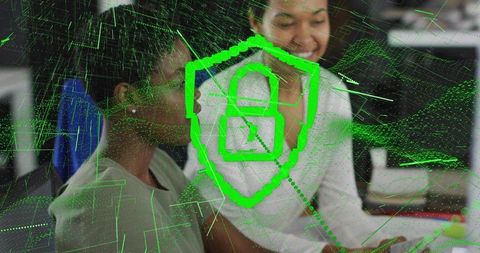 Female Colleagues Collaborating Over Cybersecurity Hologram Showing Neon Green Shield