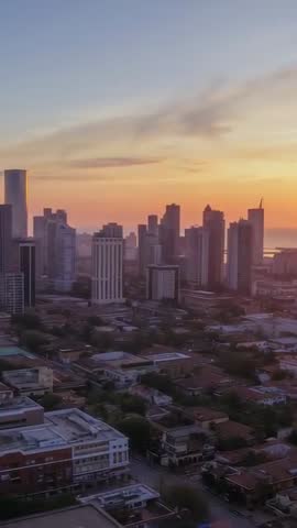 Coastal skyline at dusk vertical aerial video showing golden sunset over highrise towers
