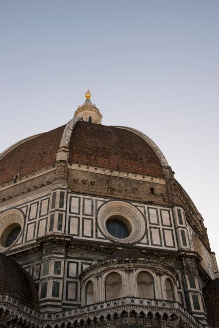 Close-up view of the iconic dome of Florence Cathedral with intricate marble work during sunset. This image is ideal for travel brochures, educational materials about Italian architecture and Renaissance history, or promoting UNESCO World Heritage sites. Captures the detailed and historic beauty of one of Italy’s most famous landmarks.