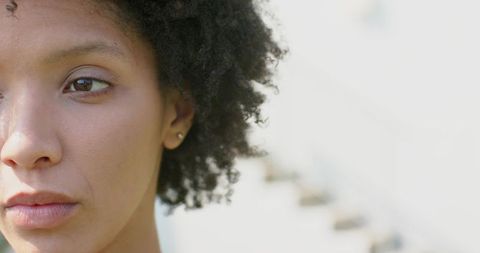 Closeup portrait of african american woman with natural curls and pensive gaze, high-key