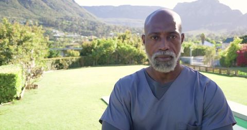 Senior african american healthcare worker wearing scrubs standing in sunlit suburban yard