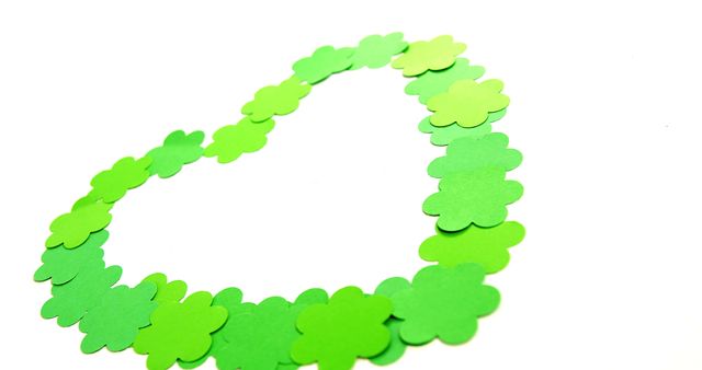 Green paper shamrocks form a heart shape on a white background, with copy space. Symbolizing St. Patrick's Day, the heart of shamrocks represents love and the Irish holiday tradition.