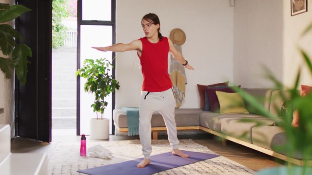 Transgender and non-binary person practicing yoga in a cozy living room, demonstrating self-care and body inclusivity. Useful for promoting fitness, mental health awareness, body positivity, and diverse representation in wellness routines.