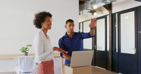 Two Professionals Discussing Work Setup in Modern Office Environment