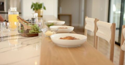 Minimal breakfast with wooden serving plank and white ceramic bowls on marble countertop