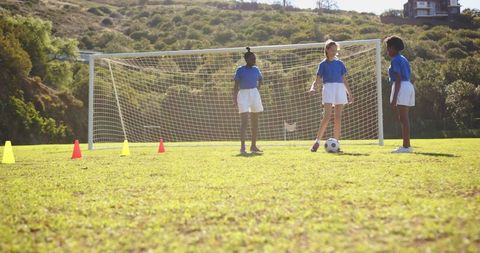 Girls Practicing Soccer Strategies with Ball and Cones
