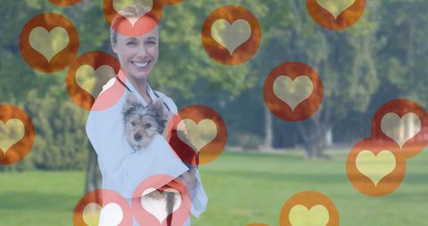 Smiling veterinarian holding small dog with heart-shaped icons