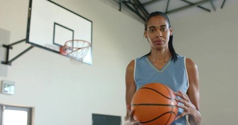 Female Basketball Player Holding Ball on Indoor Court Showing Focus and Determination
