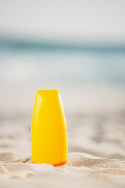 Bottle of sunscreen lotion kept on sand at beach